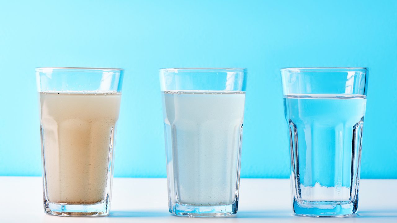 Three glasses showing untreated, partially filtered, and clear water, illustrating whole home water filtration results.